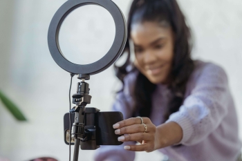 a woman setting up a ring light and a camera