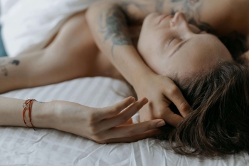 an escort and her client hugging in bed