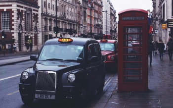 taxis on a road in London next to a phone box